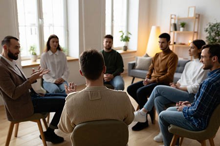 Люди сидят в кругу на стульях и общаются